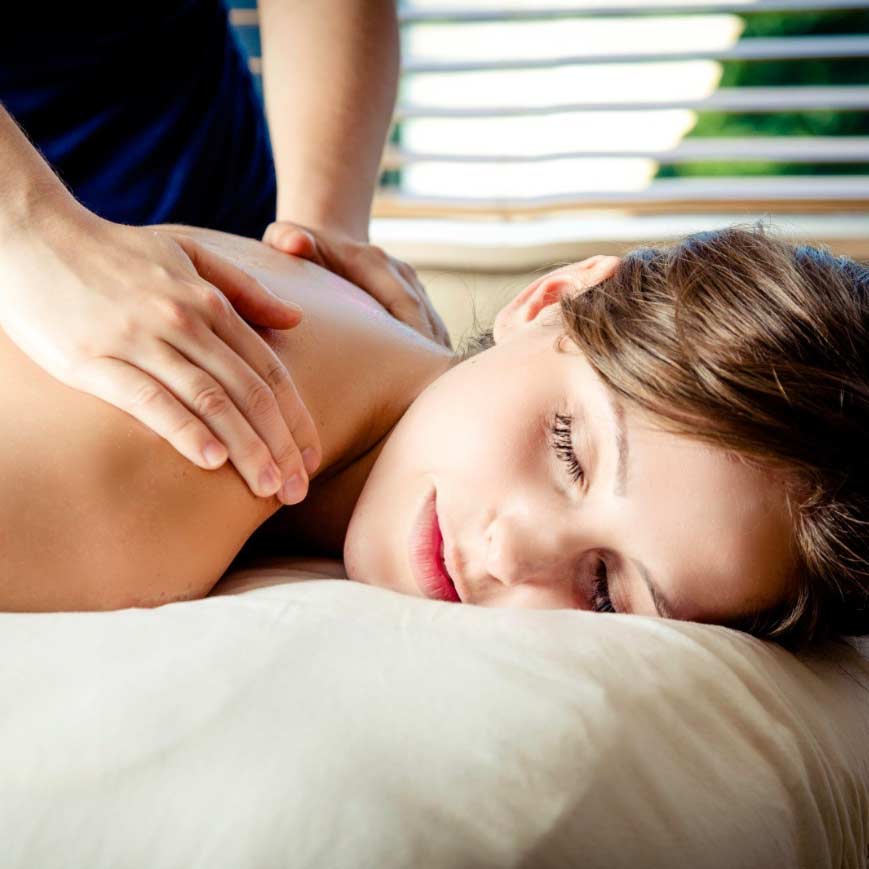 A close-up view of a person's hands providing a soothing massage on another person's back in a serene spa setting, with soft lighting and relaxing ambiance creating a tranquil atmosphere for rejuvenation.